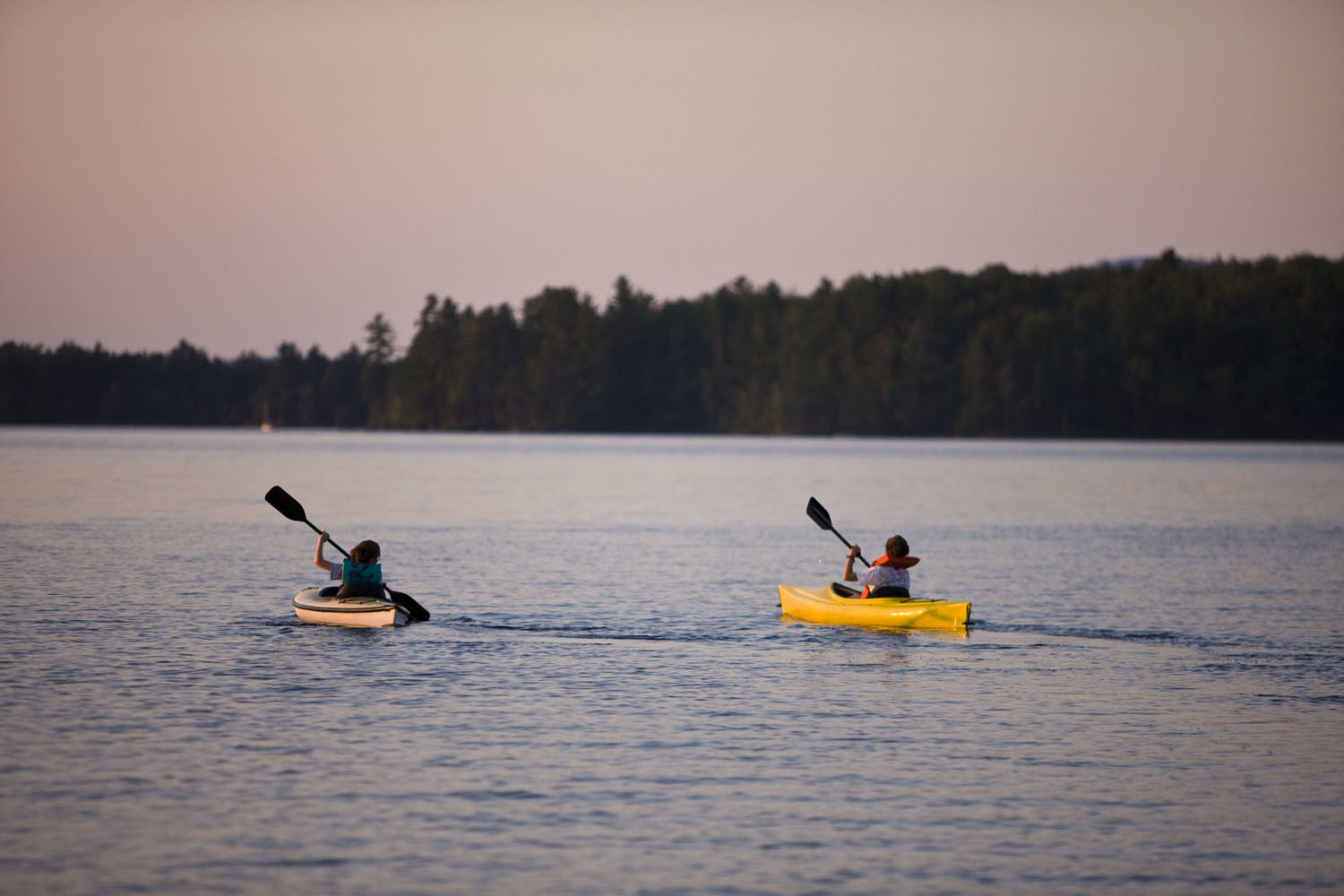 2 people kayaking on a lake at dawn