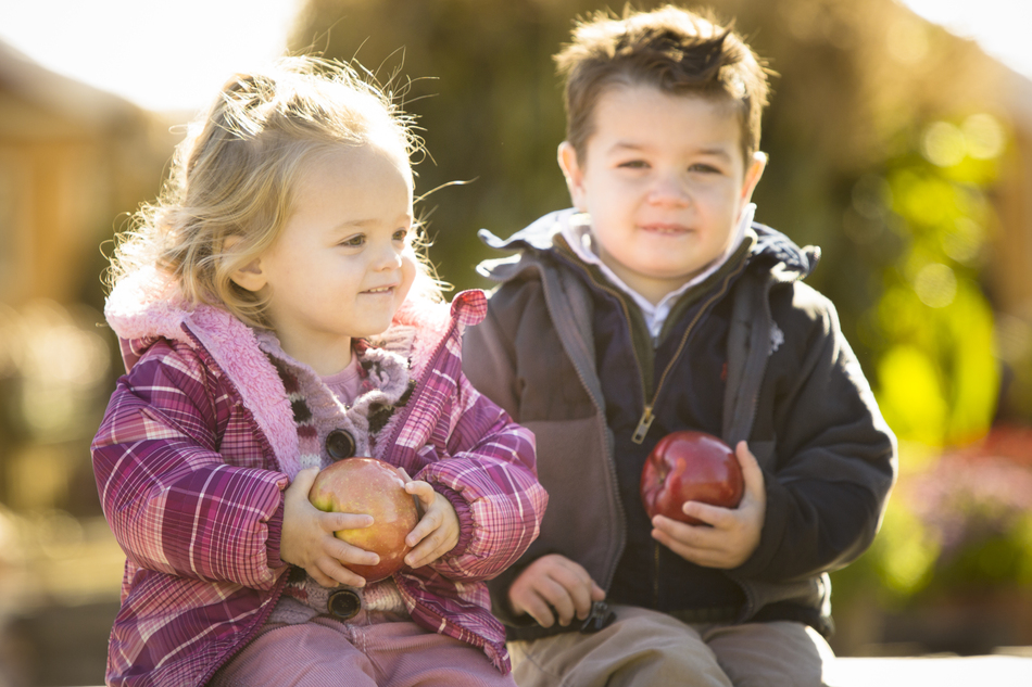 a little girl and boy holding apples
