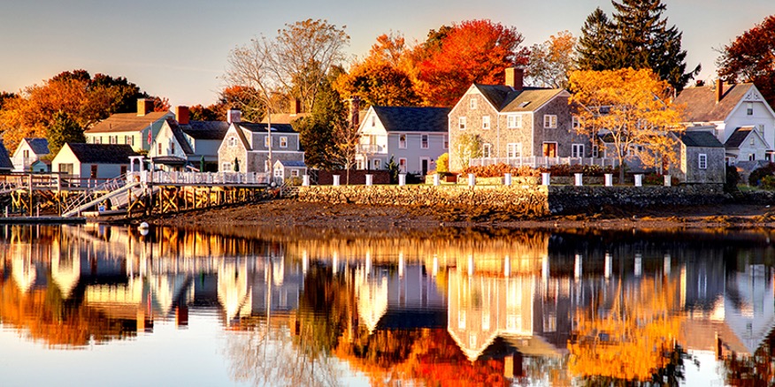 Line of homes along the waters edge and fall foliage all around at American Independence Byway