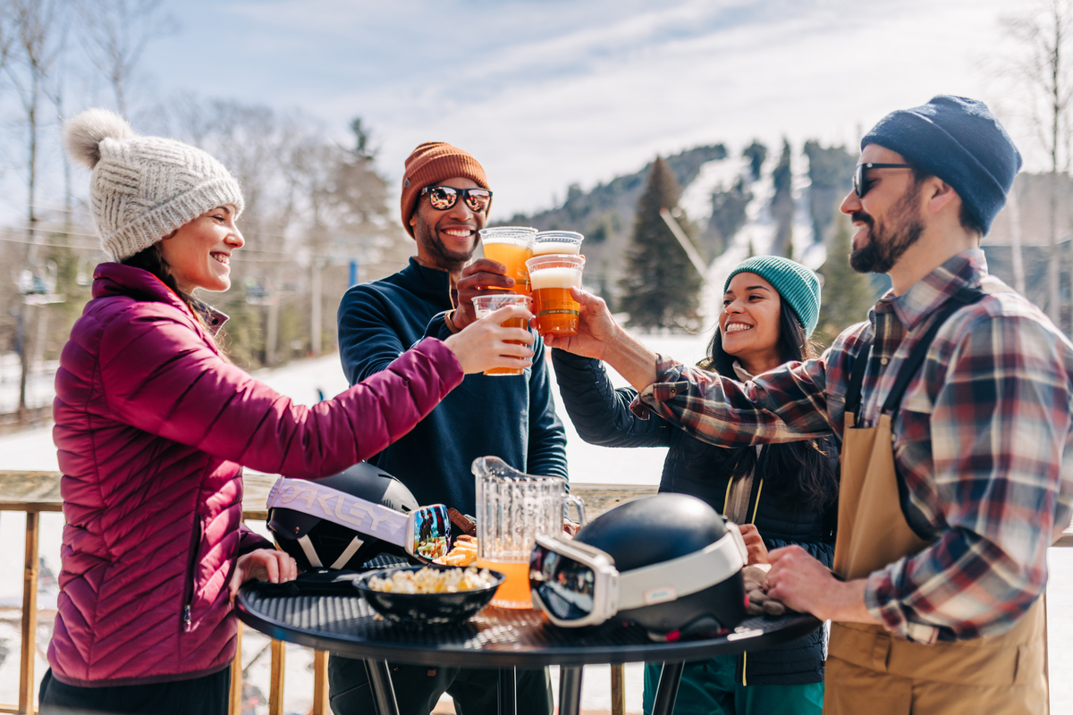 a group of people raising a toast with beers outdoors at a ski area