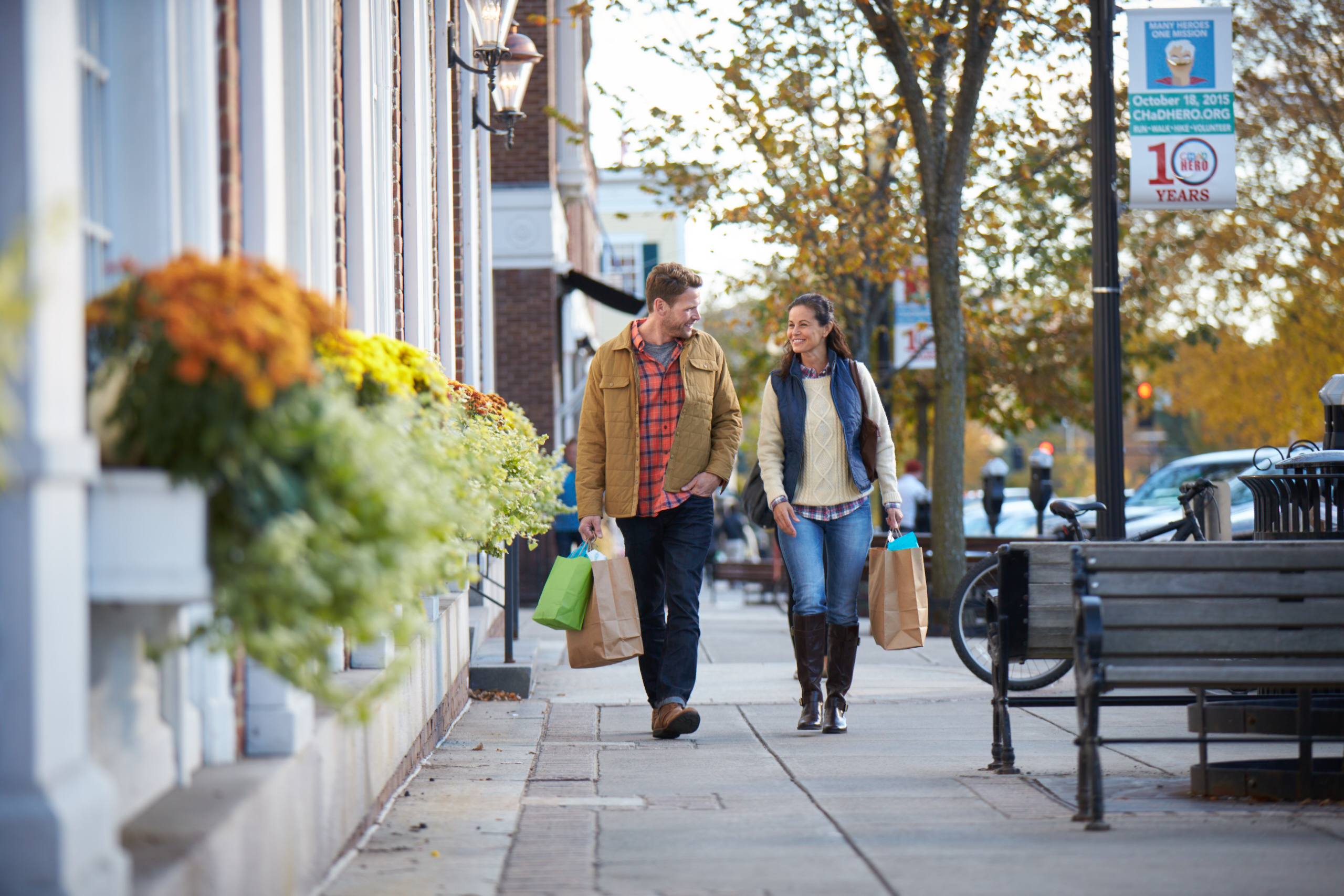 A man and a woman walking down a main street with shopping bags