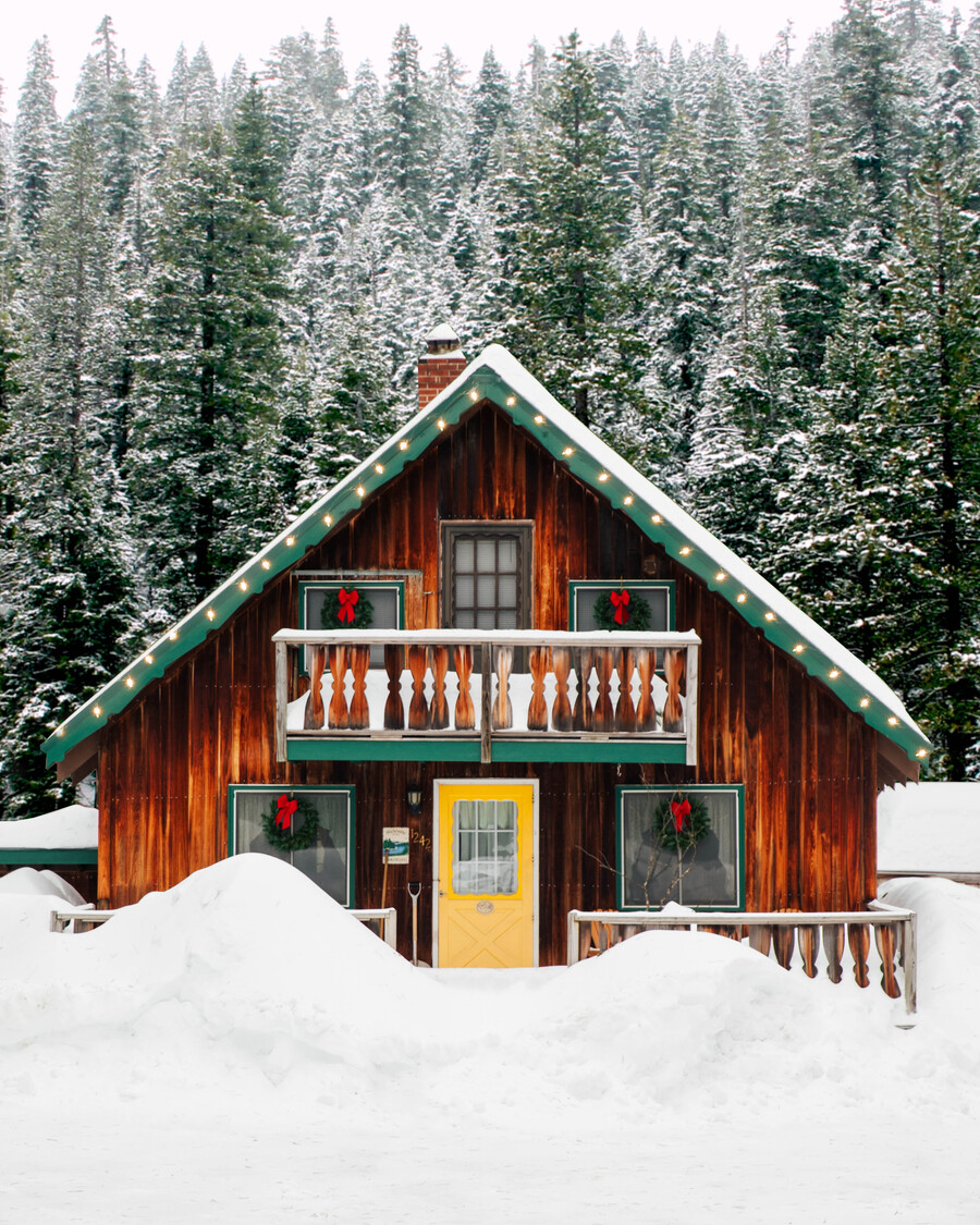 a snowcovered cottage with pine trees in background