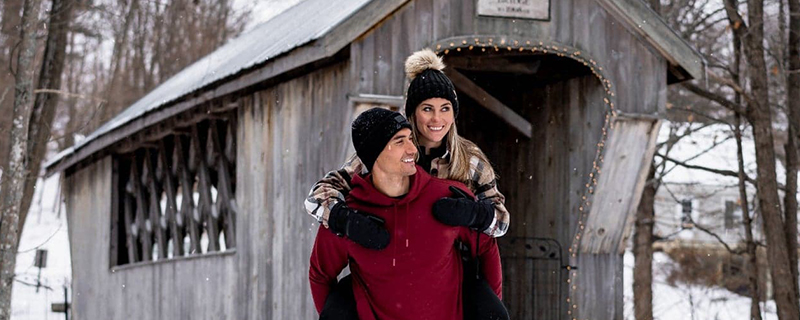a man and woman by a covered bridge in winter