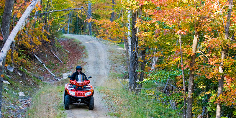 Someone driving an ATV in front of mountains of fall foliage