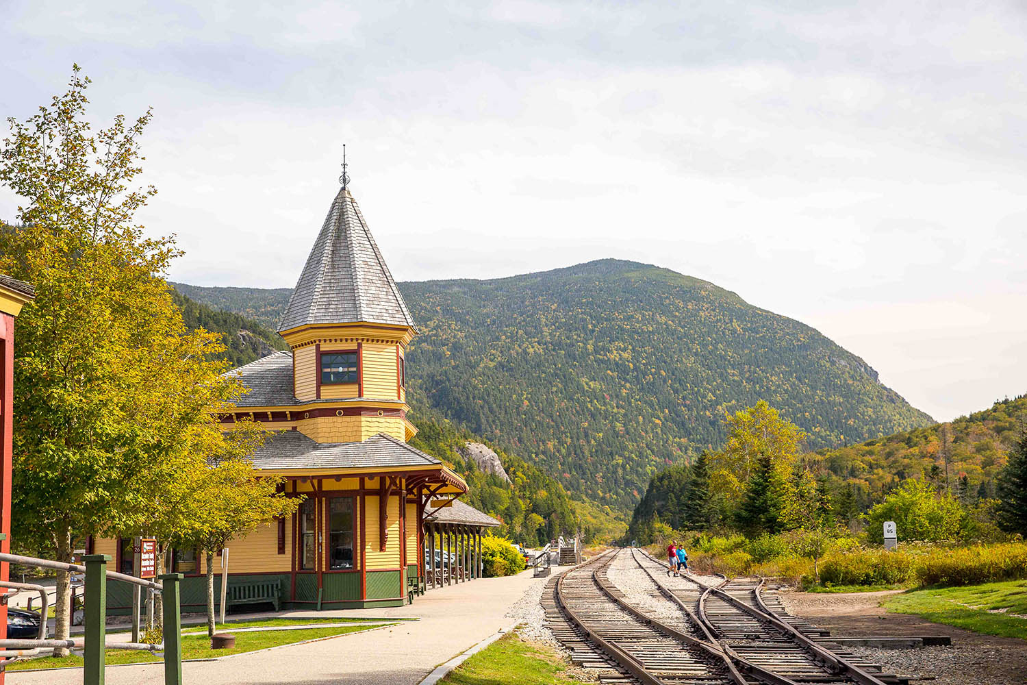 Railway station surrounded by mountains and foliage