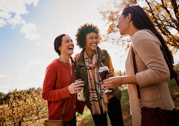 three woman standing outside drinking wine